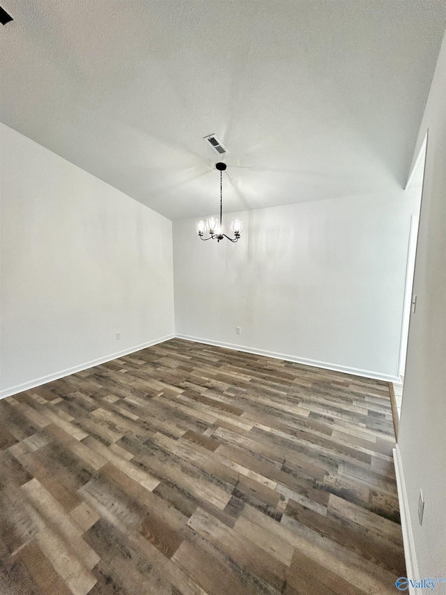 empty room featuring dark hardwood / wood-style flooring, a textured ceiling, and a chandelier