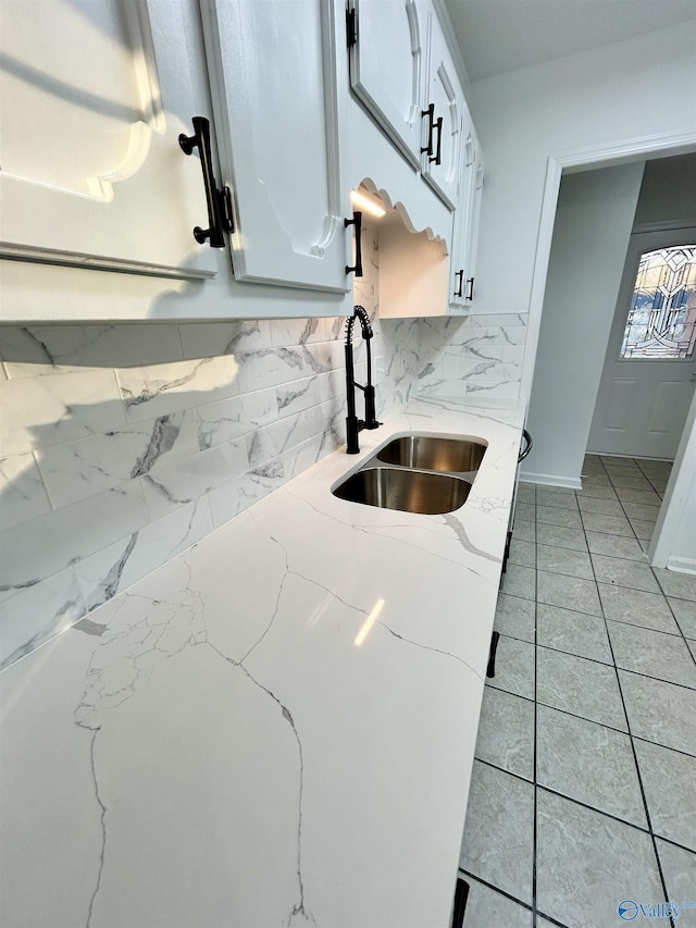 kitchen featuring sink, white cabinets, tasteful backsplash, and light stone countertops