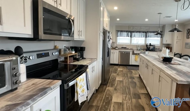 kitchen with white cabinets, hanging light fixtures, and appliances with stainless steel finishes