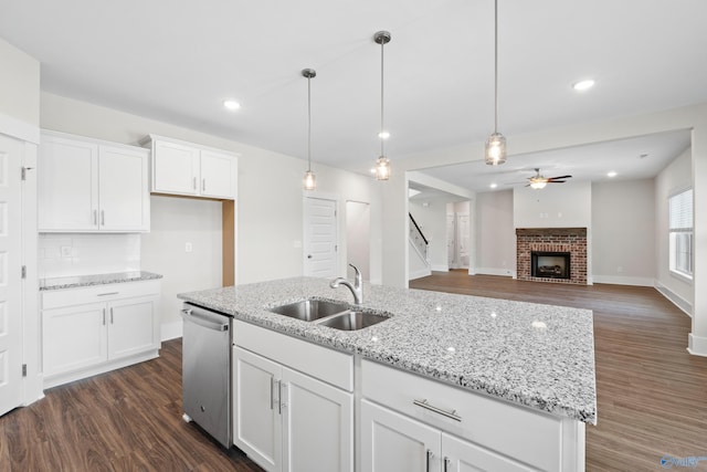 kitchen featuring pendant lighting, white cabinetry, a center island with sink, and stainless steel dishwasher