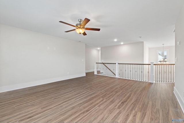 spare room with ceiling fan with notable chandelier, recessed lighting, baseboards, and wood finished floors