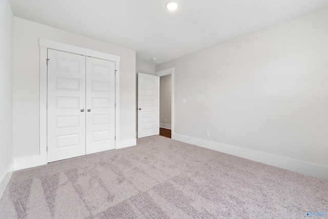 unfurnished bedroom featuring carpet floors, baseboards, and a closet