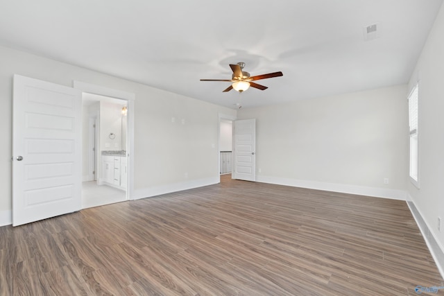 spare room featuring ceiling fan, dark wood-style flooring, visible vents, and baseboards