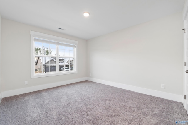 carpeted spare room featuring baseboards and visible vents