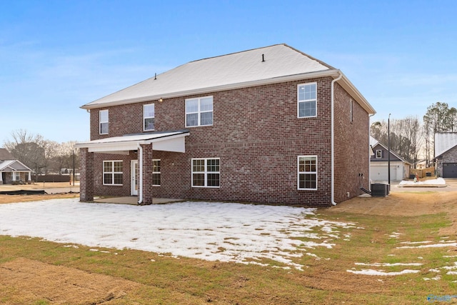 back of house with brick siding, a lawn, and central AC unit