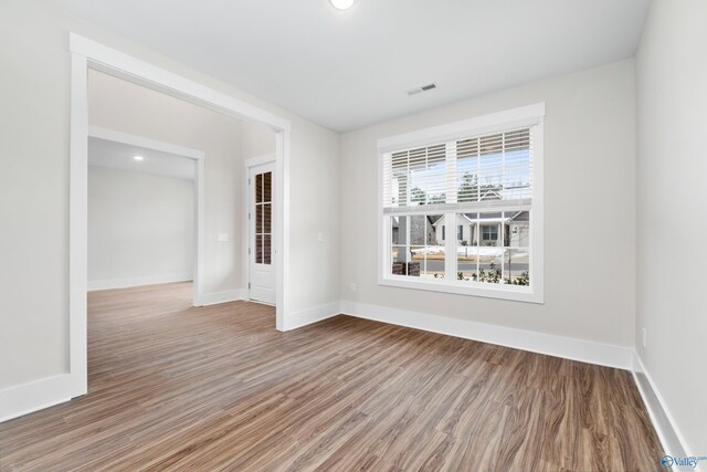 empty room featuring baseboards, visible vents, and wood finished floors