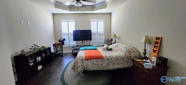 bedroom featuring a tray ceiling, ceiling fan, crown molding, and dark hardwood / wood-style flooring