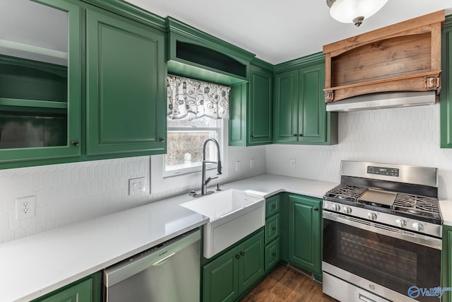 kitchen with appliances with stainless steel finishes, dark hardwood / wood-style flooring, backsplash, sink, and green cabinets