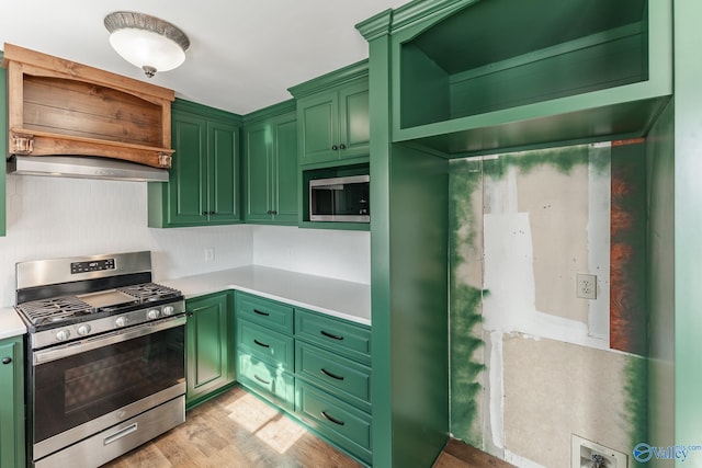 kitchen featuring extractor fan, stainless steel appliances, light hardwood / wood-style flooring, and green cabinets