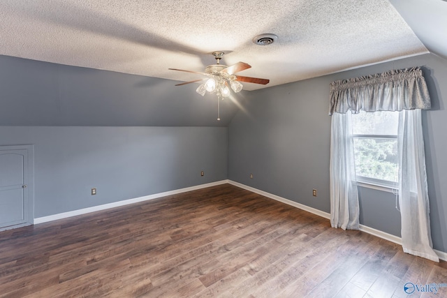 additional living space featuring dark hardwood / wood-style floors, ceiling fan, lofted ceiling, and a textured ceiling