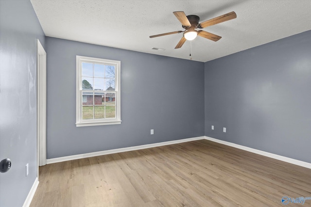 spare room with ceiling fan, a textured ceiling, and light wood-type flooring