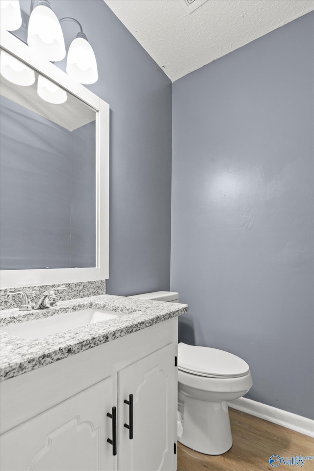 bathroom featuring vanity, hardwood / wood-style floors, a textured ceiling, and toilet