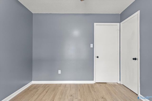 spare room featuring a textured ceiling and light hardwood / wood-style flooring