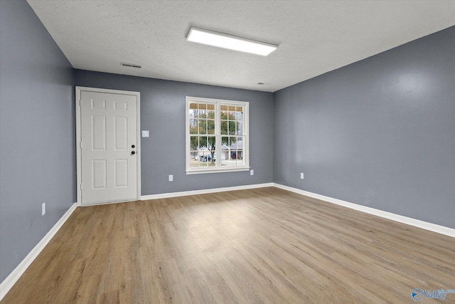 empty room with light hardwood / wood-style floors and a textured ceiling