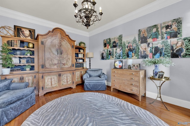 sitting room with hardwood / wood-style flooring, ornamental molding, and a chandelier