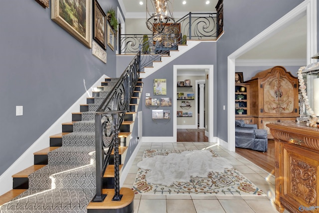 tiled foyer with a towering ceiling, ornamental molding, and a chandelier