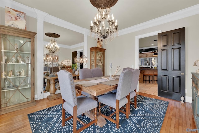 dining space featuring a notable chandelier, ornamental molding, and light hardwood / wood-style floors