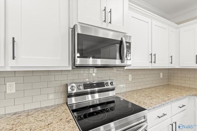 kitchen with white cabinets, light stone counters, ornamental molding, and appliances with stainless steel finishes