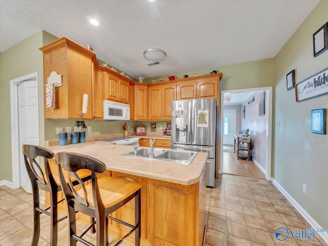 304 Santana Dr, Athens, AL 35611 - kitchen featuring white appliances, a peninsula, light countertops, a sink, and a breakfast bar area
