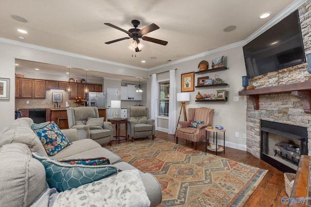 living area with ceiling fan, a fireplace, wood finished floors, crown molding, and baseboards