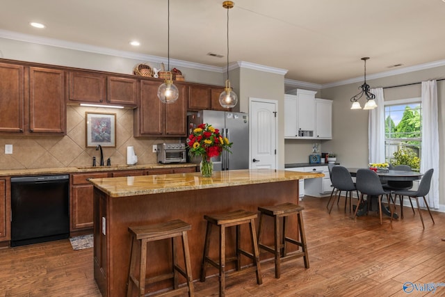 kitchen featuring black dishwasher, freestanding refrigerator, a center island, a sink, and decorative backsplash