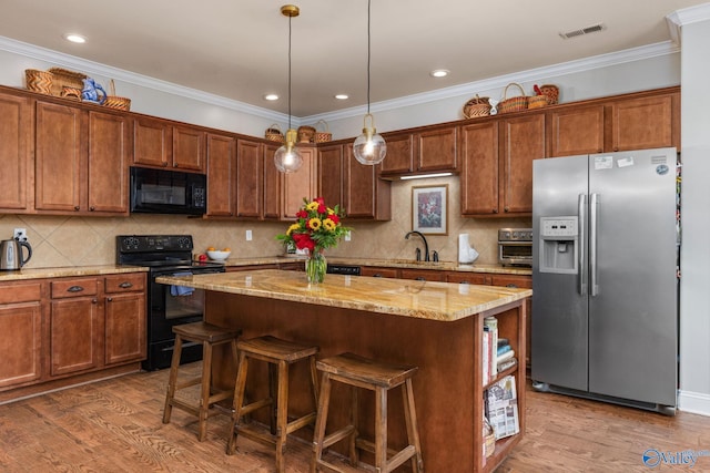 kitchen featuring black appliances, a center island, light stone counters, a kitchen breakfast bar, and wood finished floors