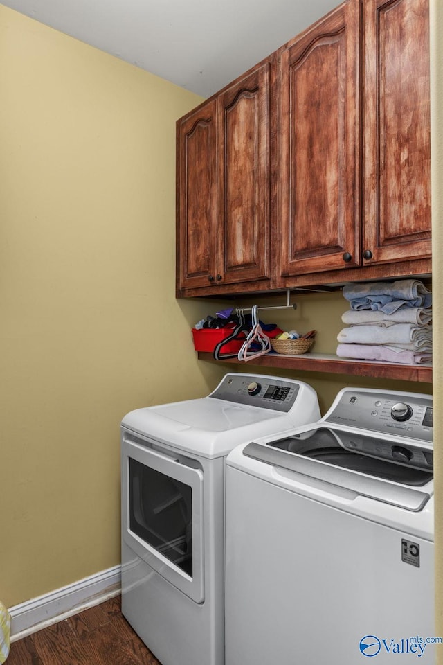 clothes washing area with washing machine and dryer, cabinet space, baseboards, and wood finished floors