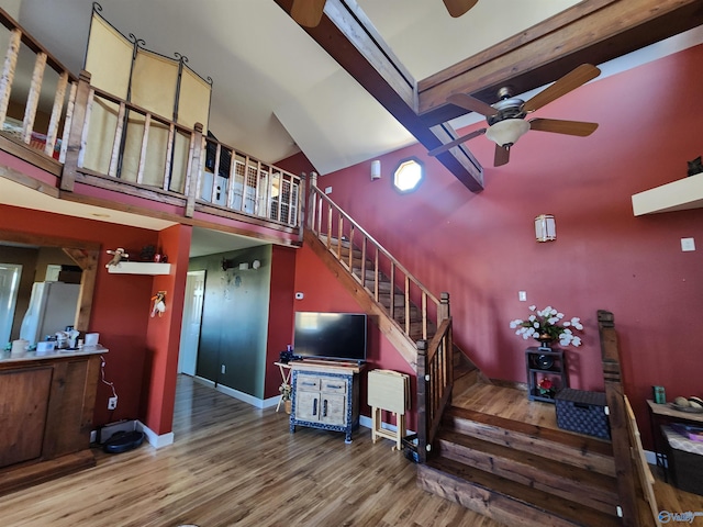 staircase featuring beamed ceiling, hardwood / wood-style flooring, high vaulted ceiling, and ceiling fan