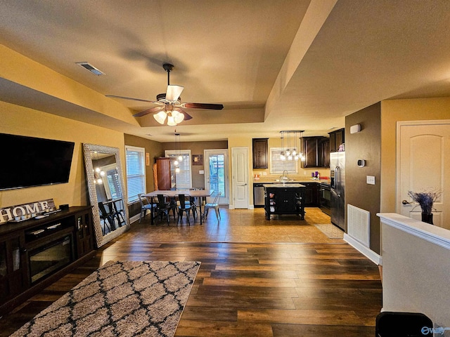 living area featuring visible vents, a raised ceiling, a ceiling fan, and hardwood / wood-style floors