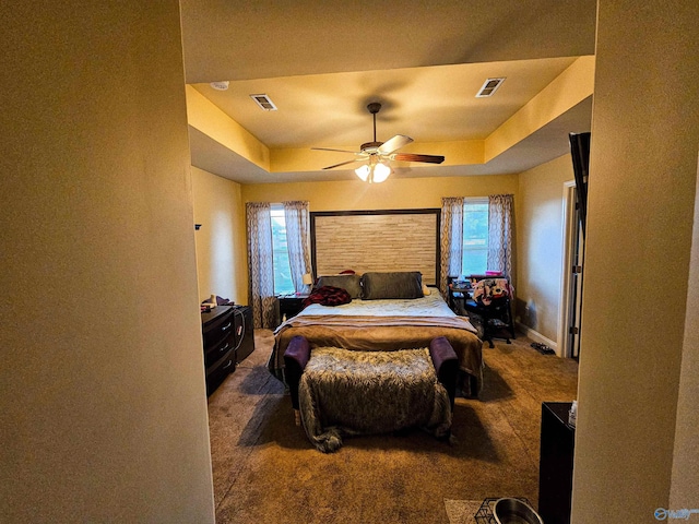 carpeted bedroom with visible vents, multiple windows, and a raised ceiling