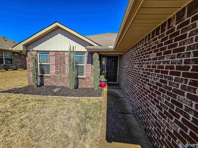 property entrance featuring brick siding and a lawn