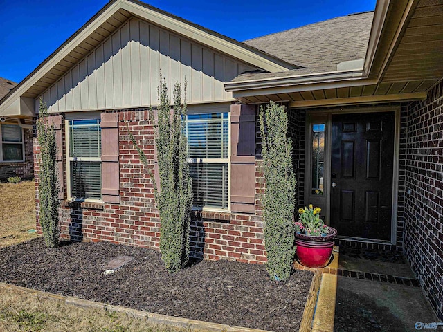 property entrance featuring brick siding and a shingled roof