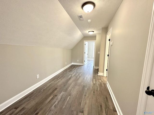 bonus room with a textured ceiling, dark wood finished floors, lofted ceiling, and baseboards