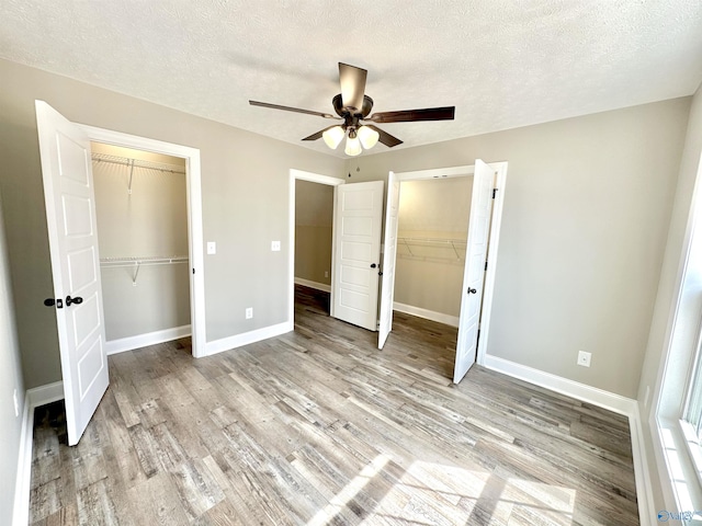 unfurnished bedroom with light wood finished floors, a closet, ceiling fan, a textured ceiling, and baseboards