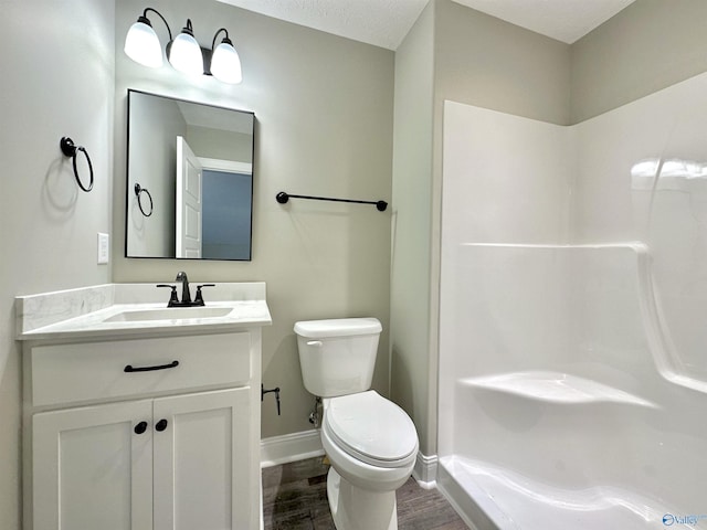 full bath featuring baseboards, a shower, toilet, wood finished floors, and vanity