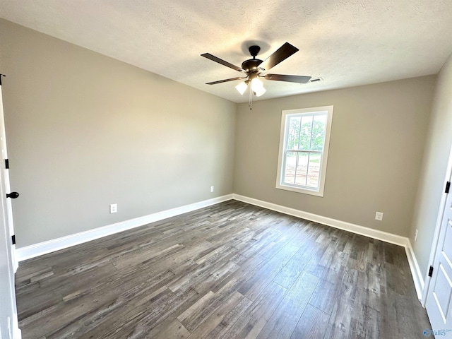 spare room with a textured ceiling, dark wood-style flooring, a ceiling fan, and baseboards