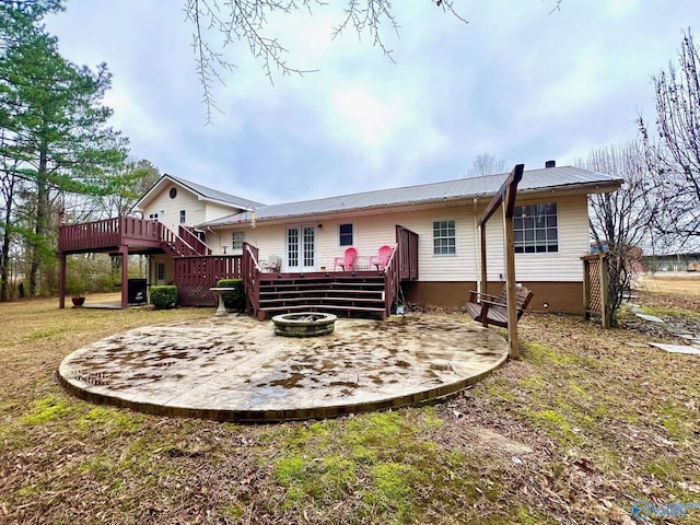 rear view of property featuring a wooden deck and an outdoor fire pit