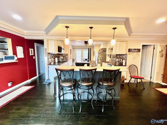 kitchen with a breakfast bar, tasteful backsplash, white cabinets, hanging light fixtures, and stainless steel appliances