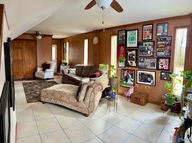 tiled living room with crown molding, ceiling fan, and wooden walls