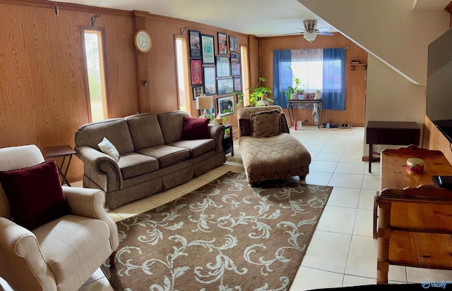 living room with light tile patterned floors, ceiling fan, and wood walls