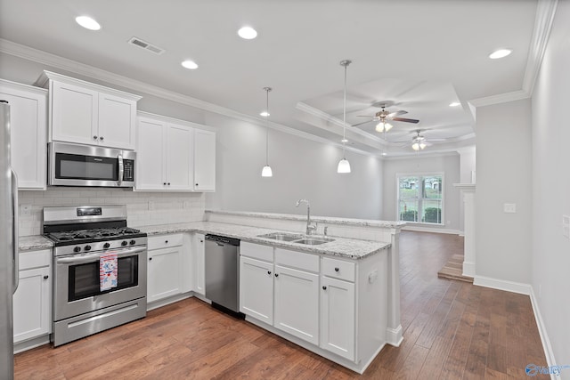 kitchen featuring white cabinets, sink, hardwood / wood-style floors, appliances with stainless steel finishes, and kitchen peninsula