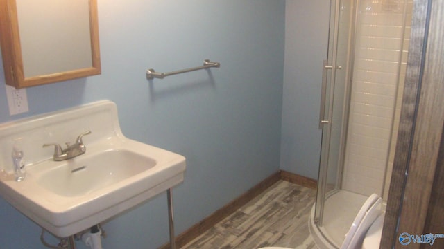 bathroom with a shower with door, hardwood / wood-style flooring, sink, and toilet