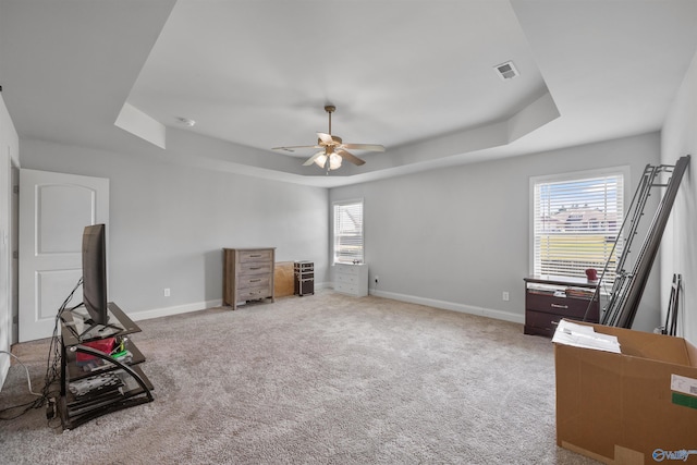 miscellaneous room with ceiling fan, light colored carpet, plenty of natural light, and a raised ceiling