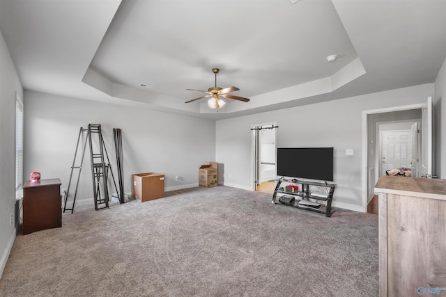 unfurnished living room featuring a raised ceiling, ceiling fan, and carpet