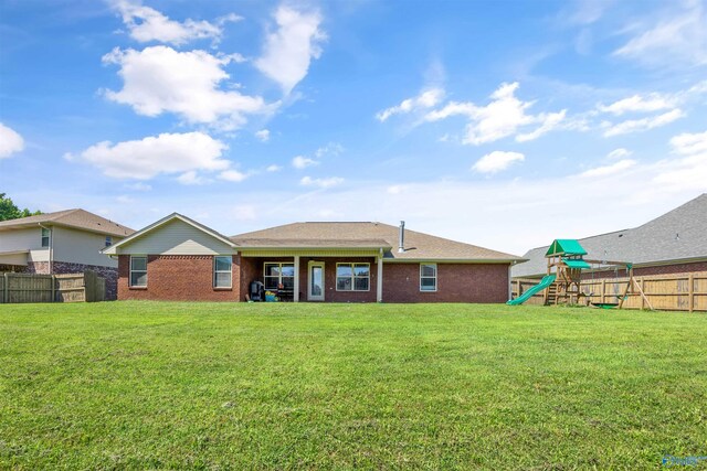 back of property featuring a lawn and a playground