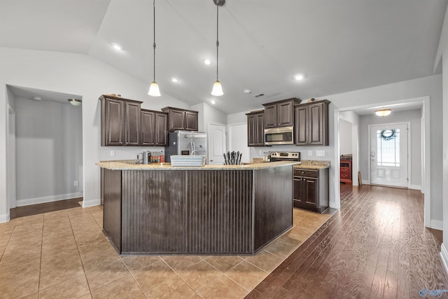 kitchen featuring pendant lighting, dark brown cabinetry, light hardwood / wood-style floors, stainless steel appliances, and a center island with sink