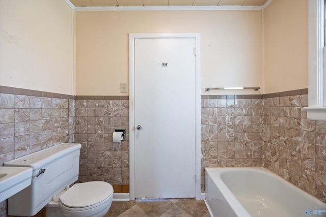 full bath featuring crown molding, wainscoting, toilet, a washtub, and tile walls
