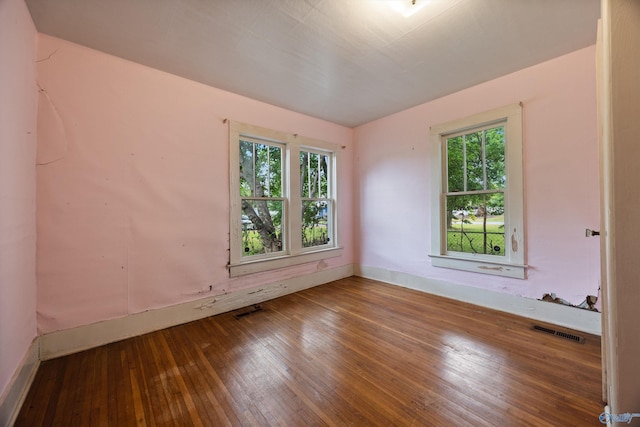 empty room featuring baseboards, wood-type flooring, and visible vents