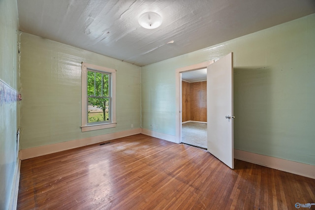 unfurnished bedroom featuring wood-type flooring, baseboards, and visible vents