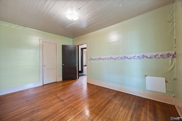 empty room with wood-type flooring and baseboards